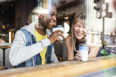 Lachende Frau, die mit einem Smartphone telefoniert und einen Kaffee mit einem Freund im Café genießt - WPEF08531