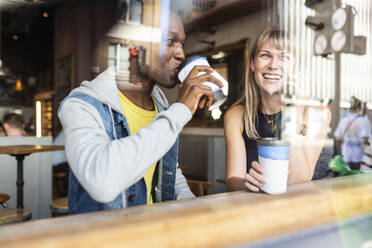 Junger Mann trinkt Kaffee mit einer Frau, die in einem Café mit ihrem Smartphone telefoniert - WPEF08532