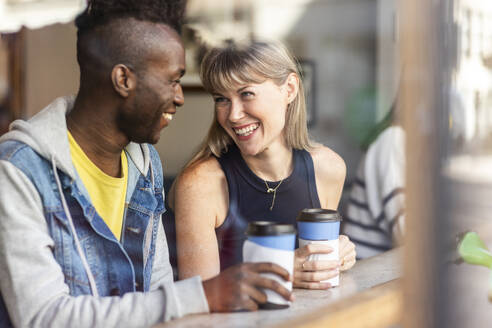 Lächelnde junge Frau bei einem Kaffee mit einem Freund in einem Café - WPEF08535