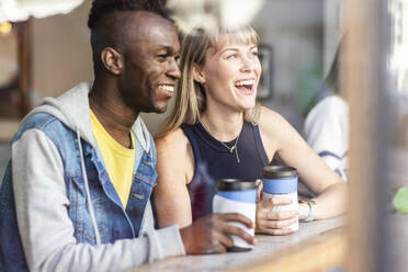 Junge glückliche Freunde schauen aus dem Fenster eines Cafés - WPEF08536