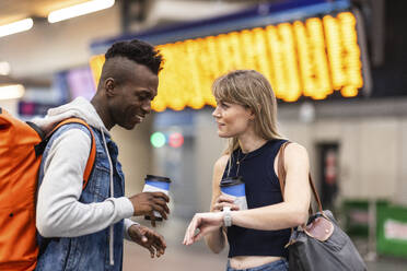 Frau, die einem Freund auf dem Bahnhof die Zeit zeigt - WPEF08547