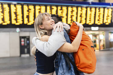 Lächelnde Frau umarmt Freund vor Abflug am Flughafen - WPEF08557