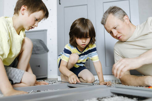Vater hilft Söhnen beim Zusammenbau des Nachttisches zu Hause - ELMF00054