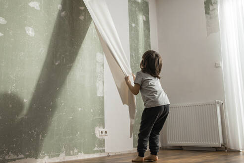 Junge löst alte Tapete von der Wand im Wohnzimmer - ELMF00081