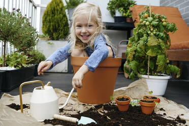 Playful girl sitting in pot at balcony - NSTF00004