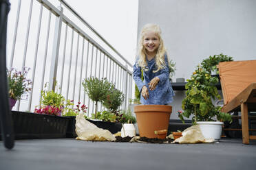 Lächelndes Mädchen bei der Gartenarbeit auf dem Balkon - NSTF00006