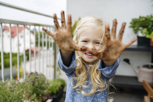Lächelndes Mädchen mit schmutzverschmierten Händen auf dem Balkon - NSTF00008