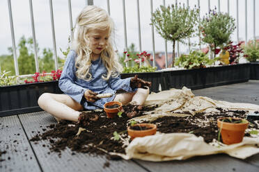 Messy girl sitting in dirt and doing gardening at balcony - NSTF00018