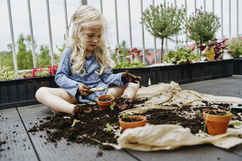 Messy girl sitting in dirt and doing gardening at balcony - NSTF00018