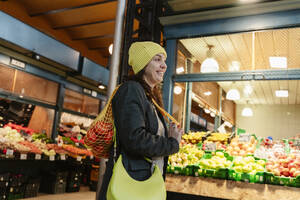 Glückliche Frau beim Einkaufen von Lebensmitteln auf dem Markt - OSF02443