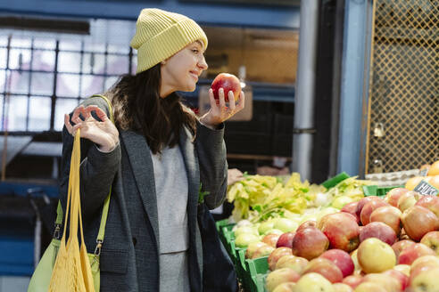 Glückliche Frau beim Aussuchen von Apfelfrüchten auf dem Markt - OSF02445