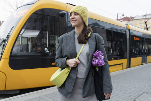 Lächelnde Frau steht in der Nähe des Zuges am Bahnsteig - OSF02455