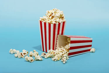 Red striped bucket with popcorn over blue background - RDTF00050