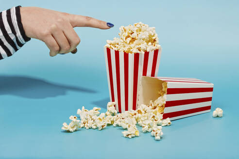Hand of woman touching popcorn in red striped container - RDTF00054