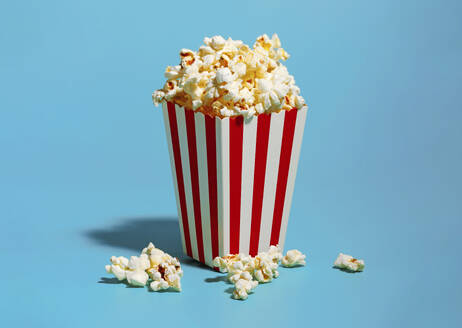 Popcorn in red striped container against blue background - RDTF00059