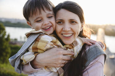 Happy mother embracing son at sunset - EYAF02963