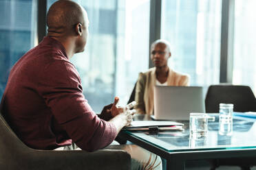 Two professionals, one male and one female, sit in a modern office. They engage in a successful discussion, demonstrating excellent teamwork. They plan and strategize in a corporate setting. - JLPSF31368