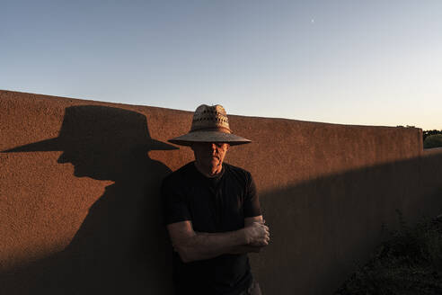 Usa, New Mexico, Santa Fe, Portrait of man in straw hat against adobe wall - TETF02556