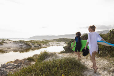 Südafrika, Hermanus, Bruder und Schwester gehen am Strand mit Bodyboards spazieren - TETF02577