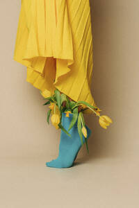 Frau auf Zehenspitzen stehend und in blauen Socken mit Tulpen vor beigem Hintergrund - VSNF01693
