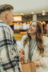 Happy young couple with shopping bags in mall - VSNF01699