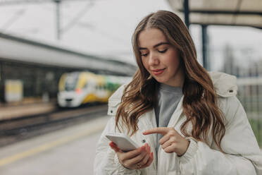 Woman using smart phone at rail station - VSNF01701