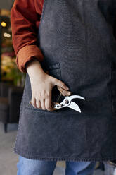 Florist holding pruning shears at store - SANF00197