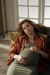 Tired pregnant woman sleeping on sofa at home - DSHF01641