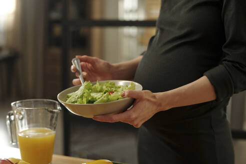 Pregnant woman with salad bowl at home - DSHF01663