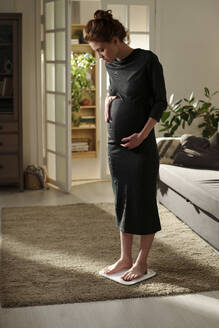 Werdende Mutter im schwarzen Kleid wiegt sich im Wohnzimmer - DSHF01664