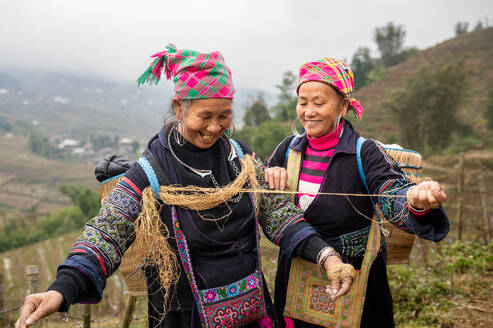 Erwachsene Vietnamesin in traditioneller Kleidung und mit Kopftuch und einem breiten Lächeln beim Sammeln von Hanffasern auf dem Land in Vietnam - ADSF53245