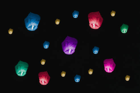 Leuchtende Papierlaternen steigen in den Nachthimmel auf und symbolisieren Hoffnungen und Träume während einer festlichen Feier. - ADSF53261
