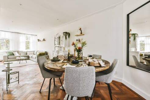 Ein elegant eingerichteter Essbereich mit einem runden Holztisch, modernen Stühlen und einem stilvollen Wohnbereich im Hintergrund. - ADSF53283