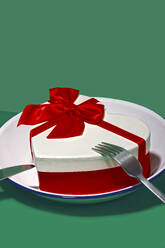 Generatives KI-Bild, das ein bezauberndes Valentinstagsgeschenk darstellt, eine herzförmige Schachtel mit einer roten Schleife, die elegant auf einem Teller platziert ist, um ein romantisches Abendessen darzustellen. - ADSF53317