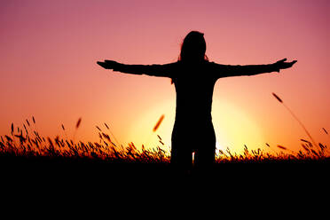 Silhouette einer jungen Frau, die sich bei einem schönen Sonnenuntergang an einem Sommertag entspannt - INGF12869