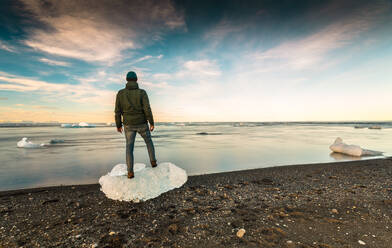 Mann steht über Eis in Jokulsarlon, Island - INGF12874