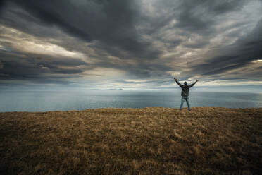 Man with arms raised enjoying the nature in Iceland - INGF12884