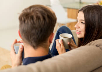 Young couple on the sofa drinking coffee - INGF12891
