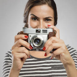 Schöne Frau hält ihre alte Kamera über das Gesicht - INGF12930