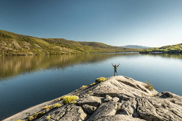 Aufnahme eines Mannes beim Wandern an einem schönen See mit erhobenem Arm - INGF12947