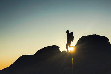 Aufnahme eines Mannes, der bei Sonnenuntergang über die Berge läuft - INGF12949