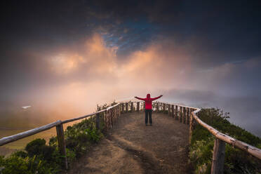 Frau steht auf einem schönen Weg mit offenen Armen bei Sonnenuntergang - INGF12957