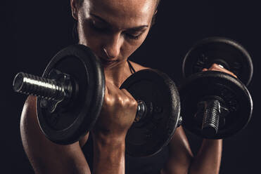 Shot of a beautiful young woman in a workout gear lifting weights - INGF12968
