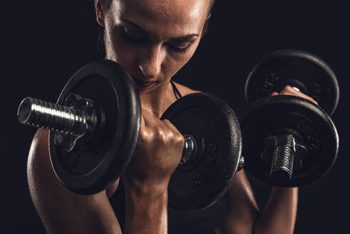 Aufnahme einer schönen jungen Frau in einem Trainingsanzug, die Gewichte hebt - INGF12968