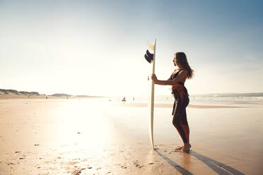Schönes Surfermädchen am Strand, das ein Surfbrett hält - INGF12982