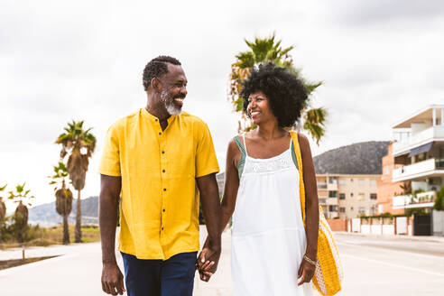 Beautiful mature black couple of lovers dating at the seaside - Married african middle-aged couple bonding and having fun outdoors, concepts about relationship, lifestyle and quality of life - DMDF10374