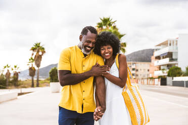 Beautiful mature black couple of lovers dating at the seaside - Married african middle-aged couple bonding and having fun outdoors, concepts about relationship, lifestyle and quality of life - DMDF10376