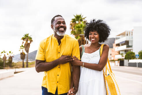 Beautiful mature black couple of lovers dating at the seaside - Married african middle-aged couple bonding and having fun outdoors, concepts about relationship, lifestyle and quality of life - DMDF10377