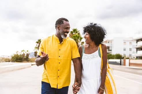 Beautiful mature black couple of lovers dating at the seaside - Married african middle-aged couple bonding and having fun outdoors, concepts about relationship, lifestyle and quality of life - DMDF10379