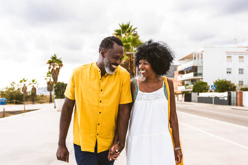 Beautiful mature black couple of lovers dating at the seaside - Married african middle-aged couple bonding and having fun outdoors, concepts about relationship, lifestyle and quality of life - DMDF10380